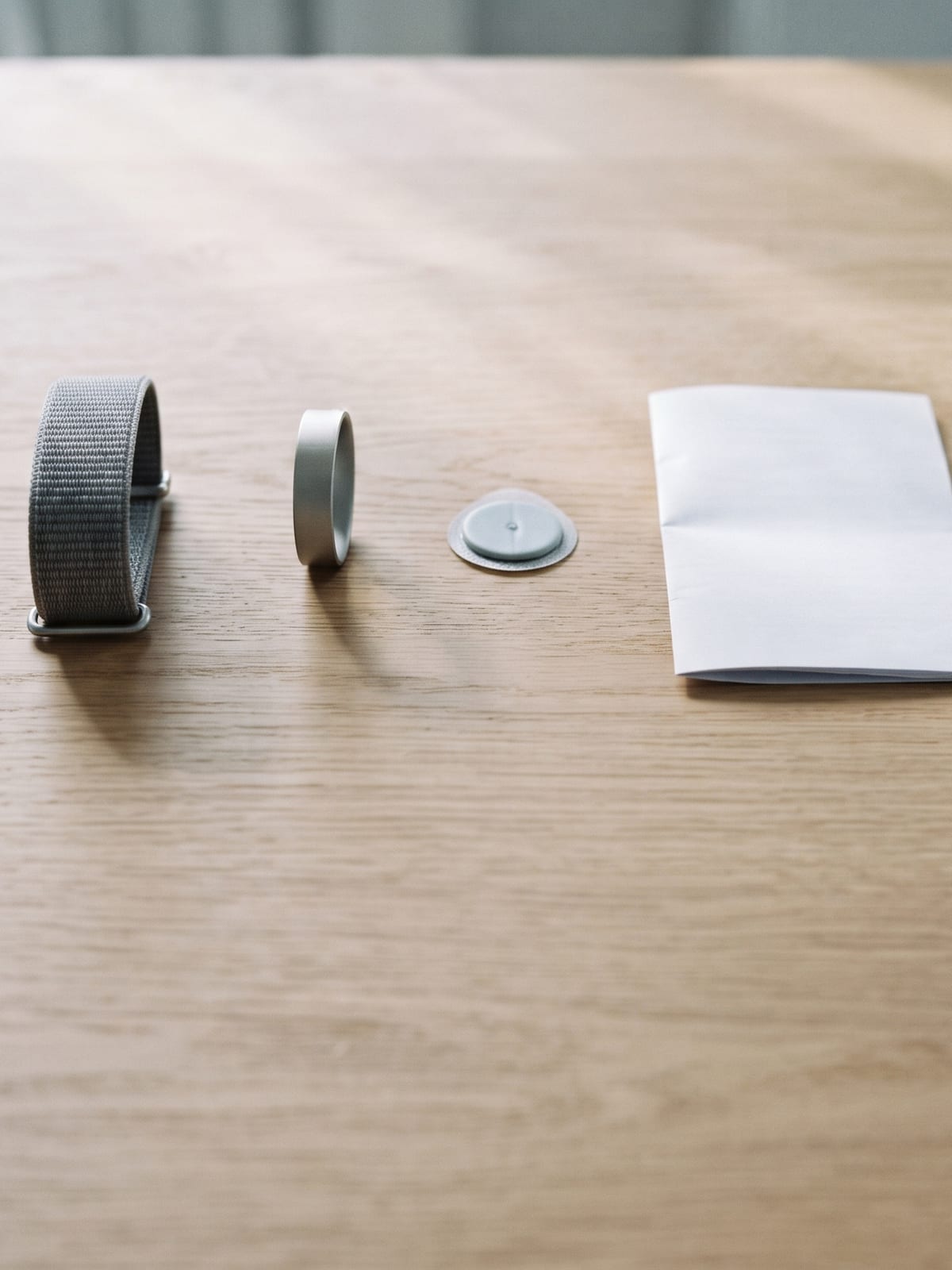 Una pulsera, un anillo y un parche alineados sobre la mesa junto a un informe